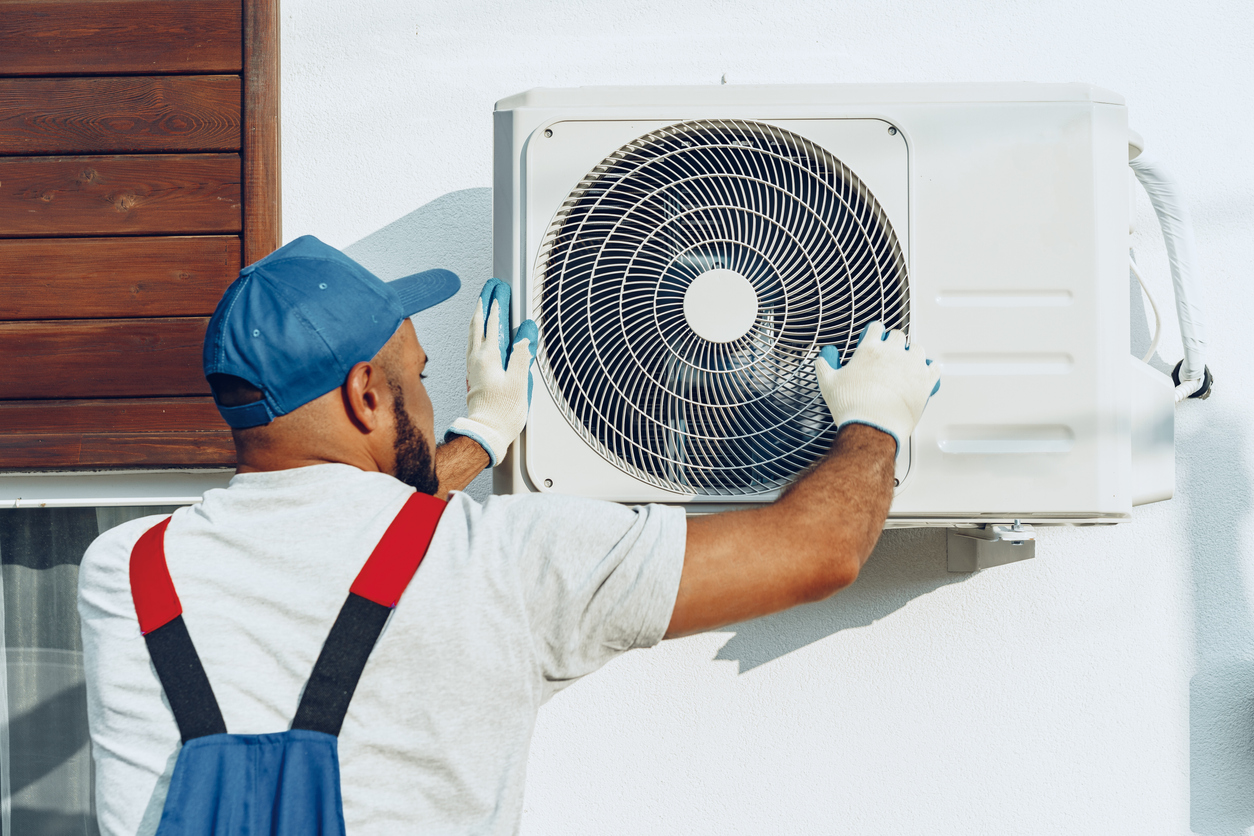 Repairman in uniform installing the outside unit of air conditioner close up